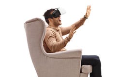 Giovane in un watchin della poltrona su una cuffia avricolare di realtà virtuale fotografia stock Giovane in un watchin della poltrona su una cuffia avricolare di realtà virtuale fotografia stock