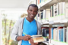 Giovane uomo africano che sorride nella libreria immagine stock libera da diritti Giovane uomo africano che sorride nella libreria immagine stock libera da diritti
