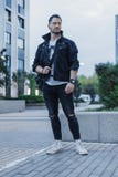Giovane uomo attraente in rivestimento nero dei jeans che sta sul fondo di paesaggio urbano immagini stock libere da diritti Giovane uomo attraente in rivestimento nero dei jeans che sta sul fondo di paesaggio urbano immagini stock libere da diritti