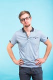 Giovane uomo dello studente su fondo blu Vetri d'uso del tipo alla moda ed esaminare macchina fotografica immagini stock libere da diritti Giovane uomo dello studente su fondo blu Vetri d'uso del tipo alla moda ed esaminare macchina fotografica immagini stock libere da diritti