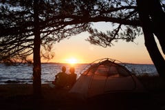 Giovane uomo e donna delle coppie che hanno resto alla tenda turistica ed al fuoco di accampamento bruciante sulla riva di mare v fotografie stock libere da diritti Giovane uomo e donna delle coppie che hanno resto alla tenda turistica ed al fuoco di accampamento bruciante sulla riva di mare v fotografie stock libere da diritti