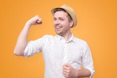Giovane uomo turistico divertente nel bicipite di manifestazioni del cappello di estate fotografie stock Giovane uomo turistico divertente nel bicipite di manifestazioni del cappello di estate fotografie stock