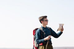 Giovane viaggiatore con lo zaino che esamina la mappa per le direzioni mentre facendo un'escursione nella campagna fotografie stock libere da diritti Giovane viaggiatore con lo zaino che esamina la mappa per le direzioni mentre facendo un'escursione nella campagna fotografie stock libere da diritti