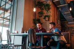 Giovani arabi che appendono in caffè del sottotetto La gente del Medio-Oriente che parla nel salotto esclude e che ha bevande immagine stock libera da diritti Giovani arabi che appendono in caffè del sottotetto La gente del Medio-Oriente che parla nel salotto esclude e che ha bevande immagine stock libera da diritti