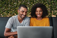 Giovani coppie sorridenti per mezzo del computer portatile fotografia stock Giovani coppie sorridenti per mezzo del computer portatile fotografia stock