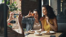 Giovani signore attraenti che prendono le foto in caffè che posa per la macchina fotografica dello smartphone video d archivio Giovani signore attraenti che prendono le foto in caffè che posa per la macchina fotografica dello smartphone video d archivio