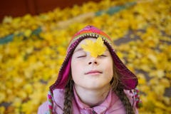 Girl in autumn clothes and funny hat on the background of yellow leaves looking up to the right. royalty free stock image Girl in autumn clothes and funny hat on the background of yellow leaves looking up to the right. royalty free stock image