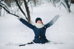 girl in a black jacket and a black hat sits on a string in the snow and throws snow. Happy child after a snowfall. Snow on the tre stock photos girl in a black jacket and a black hat sits on a string in the snow and throws snow. Happy child after a snowfall. Snow on the tre stock photos