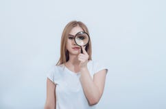 Girl with blond hair is holding a magnifying glass. Enlarged eye. Smile. Research search