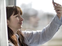 Young girl in a blue shirt makes selfie by the window royalty free stock photos Young girl in a blue shirt makes selfie by the window royalty free stock photos