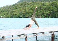 Girl exercising yoga pose three-legged downward dog on jetty by sea stock images Girl exercising yoga pose three-legged downward dog on jetty by sea stock images