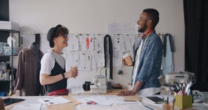 Girl and guy workers of fashion studio talking holding coffee to go relaxing stock video footage Girl and guy workers of fashion studio talking holding coffee to go relaxing stock video footage