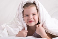 The girl hid her head under a white blanket, looked and smiled stock image The girl hid her head under a white blanket, looked and smiled stock image