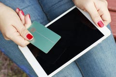 Girl holding a credit card in her hand and tablet, outdoors, concept of online shopping, Cyber Monday stock photos Girl holding a credit card in her hand and tablet, outdoors, concept of online shopping, Cyber Monday stock photos