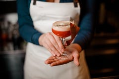 Girl holding an orange cocktail with the white scum in the glass royalty free stock photography Girl holding an orange cocktail with the white scum in the glass royalty free stock photography