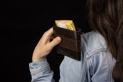Girl holding a purse with money euro back view, close-up, black background, shopping royalty free stock photo Girl holding a purse with money euro back view, close-up, black background, shopping royalty free stock photo
