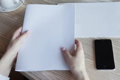 The girl holds the magazine in hand. Nearby phone on a table lies. stock photography The girl holds the magazine in hand. Nearby phone on a table lies. stock photography