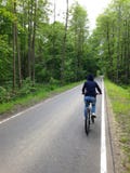 A girl in a hoodie rides a bicycle on an asphalt path stock photo A girl in a hoodie rides a bicycle on an asphalt path stock photo
