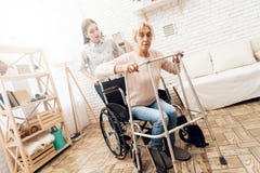Girl is nursing elderly woman at home. Woman is trying to stand up from wheelchair. royalty free stock image Girl is nursing elderly woman at home. Woman is trying to stand up from wheelchair. royalty free stock image