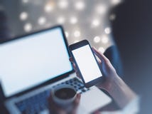 Girl pointing finger a black smartphone and using open laptop with a empty blank screen monitor and a cup of coffee or tea stock images Girl pointing finger a black smartphone and using open laptop with a empty blank screen monitor and a cup of coffee or tea stock images