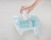 The girl pours a glass of water on a baby diaper, close-up stock photo The girl pours a glass of water on a baby diaper, close-up stock photo