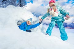 Girl pull boy out of snow cave in park Royalty Free Stock Photos Girl pull boy out of snow cave in park Royalty Free Stock Photos