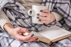 Girl Reading Book And Holding Cup Of Coffee And Covered With Retro Blanket Stock Photos