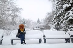 Girl reading in the snow, sitting on a bench