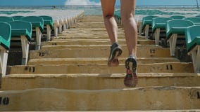 Girl running upstairs at a stadium. Close-up stock footage Girl running upstairs at a stadium. Close-up stock footage