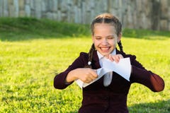 Girl in school uniform sits on grass and rips a piece of paper royalty free stock images Girl in school uniform sits on grass and rips a piece of paper royalty free stock images