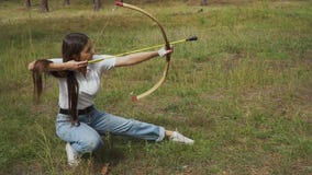 Girl shooting with bow from a sitting position