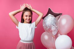 Girl shows Bunny ears, birthday party on pink background, with balloons stock photo Girl shows Bunny ears, birthday party on pink background, with balloons stock photo