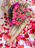 A girl sits on a bed with a pink bouquet of flowers. A gift for the holiday. Female feet. stock images A girl sits on a bed with a pink bouquet of flowers. A gift for the holiday. Female feet. stock images