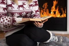 Girl Sitting In Front Of The Fireplace And Reading Book In Long Winter Night At Home Royalty Free Stock Photos