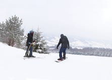 Girl skier and guy snowboarder stand on the background of snow-capped mountains, preparing for slalom. Modern sports equipment for royalty free stock photos Girl skier and guy snowboarder stand on the background of snow-capped mountains, preparing for slalom. Modern sports equipment for royalty free stock photos