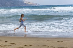 Girl in striped t-shirt running along the beach stock images Girl in striped t-shirt running along the beach stock images