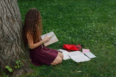Girl student holding book and sitting under tree Stock Photography Girl student holding book and sitting under tree Stock Photography