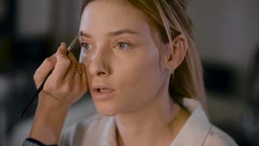 Girl stylist working in a beauty studio. Make-up for a beautiful blonde. Working with shadow stock footage Girl stylist working in a beauty studio. Make-up for a beautiful blonde. Working with shadow stock footage