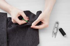 Girl tailor rips thread on a gray waistcoat. stock images Girl tailor rips thread on a gray waistcoat. stock images