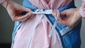 The girl ties up an apron. Hands closeup. royalty free stock images The girl ties up an apron. Hands closeup. royalty free stock images