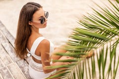 Girl on a tropical beach in white swimsuit and sunglasses posing stock photo Girl on a tropical beach in white swimsuit and sunglasses posing stock photo