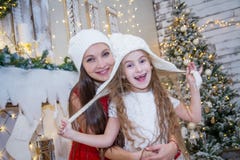 Girl in white hat with mother under Christmas tree Stock Photo Girl in white hat with mother under Christmas tree Stock Photo