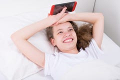 Girl who is sick and lies in bed, plays in phone and smiles stock photo Girl who is sick and lies in bed, plays in phone and smiles stock photo