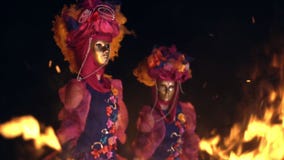 Girls in a Venetian masquerade costume dancing in the open air. on the faces of people of the mask without emotion.