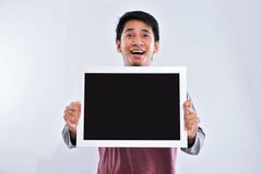 Gl?cklicher junger h?bscher asiatischer Mann, der die leere Tafel oder Brett bereit zu Ihrem Text h?lt und zeigt lizenzfreies stockfoto Gl?cklicher junger h?bscher asiatischer Mann, der die leere Tafel oder Brett bereit zu Ihrem Text h?lt und zeigt lizenzfreies stockfoto