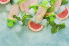 Glaces à l'eau faites maison de pamplemousse avec des tranches de pamplemousse sur un fond en bois en bon état Images stock Glaces à l'eau faites maison de pamplemousse avec des tranches de pamplemousse sur un fond en bois en bon état Images stock