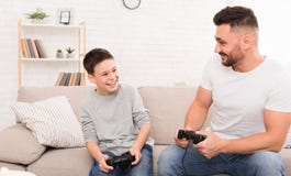 Gladlynt fader och son som hemma spelar videospelet royaltyfri fotografi Gladlynt fader och son som hemma spelar videospelet royaltyfri fotografi