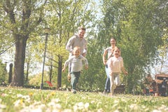 Gladlynt familj som spelar med deras barn` s i ängen arkivfoto Gladlynt familj som spelar med deras barn` s i ängen arkivfoto