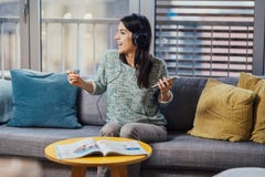 Gladlynt kvinna som lyssnar till musik med stor hörlurar och att sjunga Tycka om att lyssna till musik i fri tid hemma Koppla av royaltyfri bild Gladlynt kvinna som lyssnar till musik med stor hörlurar och att sjunga Tycka om att lyssna till musik i fri tid hemma Koppla av royaltyfri bild