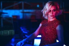 Glam blond woman sitting at the bar in the night club in colourful neon lights and looking aside royalty free stock image Glam blond woman sitting at the bar in the night club in colourful neon lights and looking aside royalty free stock image